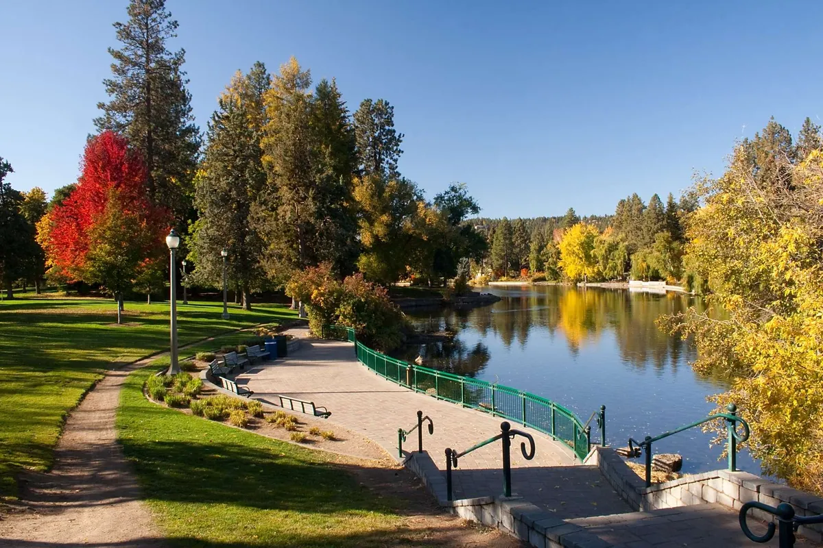 A picturesque lake bordered by colorful trees and a green walking path, inviting residents and guests to enjoy walks, picnics, and community events amidst tranquil scenery.