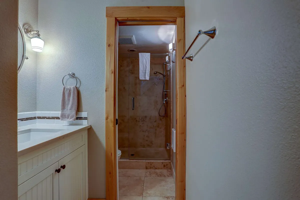 A serene bathroom with a modern vanity and sink, a spacious shower area, and a towel rack, all designed with calming tones. The space feels both functional and spa-like, inviting guests to unwind and refresh after outdoor activities.